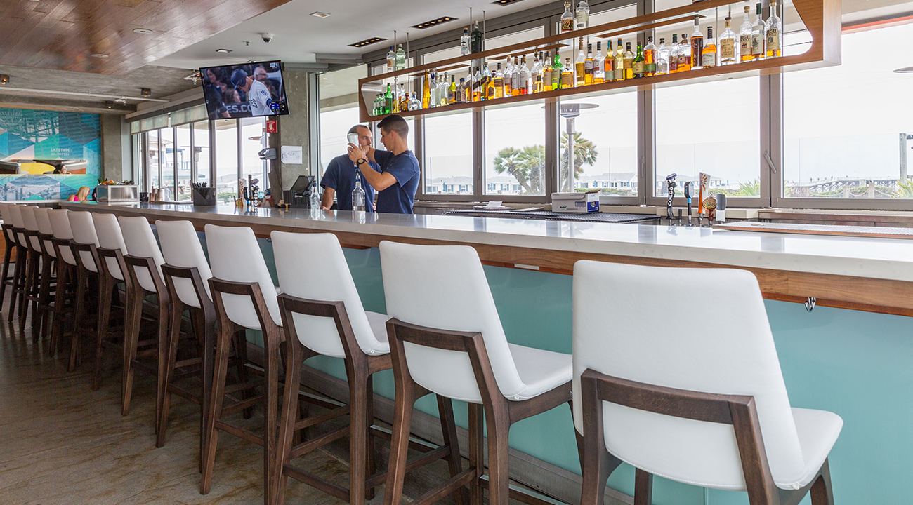 Bar at JRDN with white high top chairs and view of the ocean
