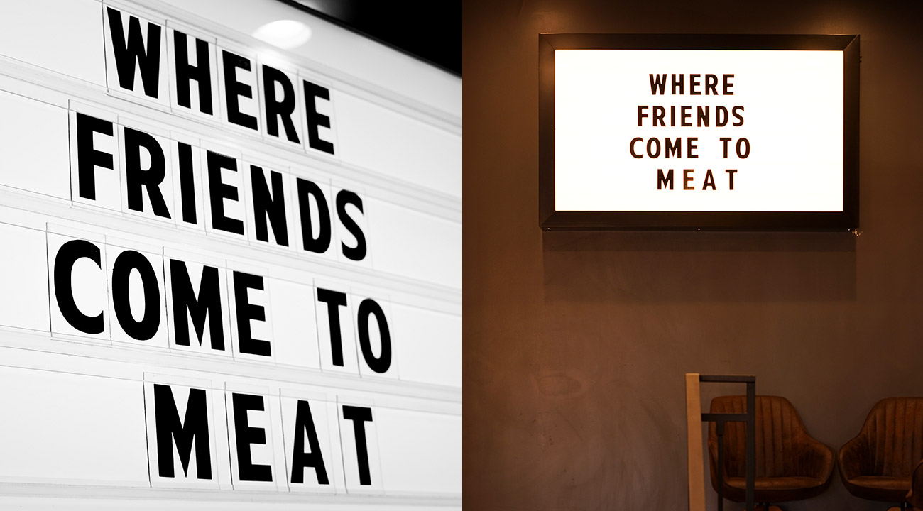 LED light box mounted on restaurant wall that says "Where friends come to meat," spelled M-E-A-T