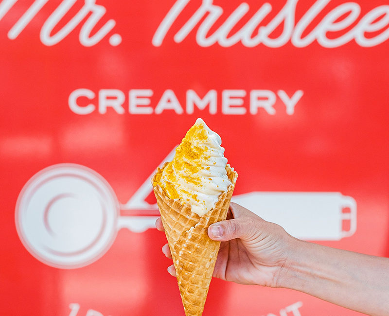 Hand holding waffle cone in front of Mr. Trustee branded sign